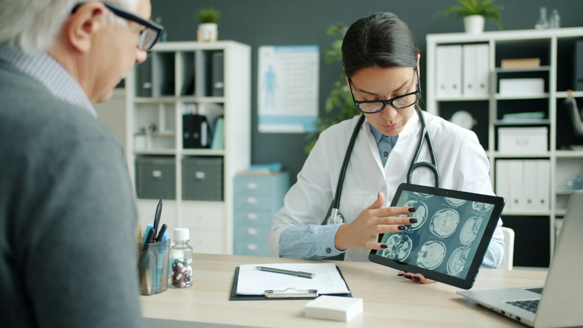 Médica muestra resultados de imágenes diagnósticas a un paciente en una tableta